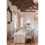 Eleganter Hochzeitssaal mit gepolsterten Stühlen, langer gedeckter Festtafel, Lichterketten und rustikalen Holzbalken.