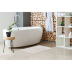 Weisser Badezimmerteppich vor freistehender Badewanne mit Holzwand-Dekor und modernem Spa-Ambiente