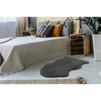 Dunkelgraues Kunstfell Cosy als Bettvorleger im modernen Schlafzimmer mit Holz-Nachttisch und Pflanzen