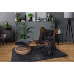 Dunkelgraue Kuscheldecke auf Ledersessel mit grauem Teppich und Samtkissen in modernem Wohnzimmer