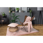 Kuschelige rosa Felldecke auf Leder-Schmetterlingsstuhl mit passendem Kissen und Teppich im modernen Wohnzimmer