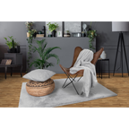 Hellgraue Kuscheldecke auf braunem Ledersessel mit passendem Kissen und Teppich in modernem Wohnzimmer