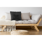 Dunkelgraues Flausch-Dekokissen auf hellem Holzsofa mit Naturdekor und Weidenpuff im Boho-Stil