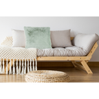 Mintgrünes Flauschkissen auf Holzsofa mit beigen Kissen, Makramee-Decke und Rattan-Hocker