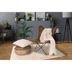 Cremefarbene Kuscheldecke Heaven auf braunem Leder-Butterfly-Chair mit Dekokissen und Pouf im modernen Wohnzimmer