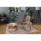 Weiche Kuscheldecke in Beige auf Ledersessel mit Ottomane und Kissen auf Fellimitat-Teppich
