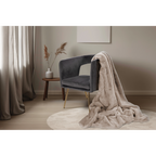 Beige Flauschdecke Lalee Heaven auf grauem Samtsessel mit Goldbeinen im modernen Wohnzimmer
