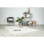 Lalee Elif Teppich in Creme mit Wellenmuster in modernem Wohnzimmer mit grauem Sessel und Designermöbeln