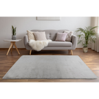 Silbergrauer Hochflor-Teppich Lalee Dolce im Wohnzimmer mit grauem Sofa und Holzboden