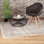 Lalee Paris Teppich Pierre Cardin Silver 160x230cm in modernem Wohnzimmer mit Draht-Couchtisch und Sessel