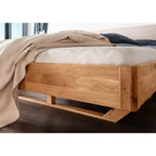 Balkenbett aus Holz mit beigem Bettwäsche und schwarzem Kissen in modernem Schlafzimmer Design.