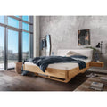 Balkenbett aus Holz mit Cordkopfteil in modernem Schlafzimmer mit großen Fenstern und minimalistischer Einrichtung.