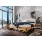 Balkenbett aus Holz mit Cordkopfteil in modernem Schlafzimmer mit großen Fenstern und minimalistischer Einrichtung.