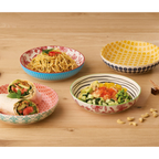 Bunte Keramikschalen mit Mustern auf Holztisch, gefüllt mit Pasta, Salat und Wraps – Küchenprofis Amici-Serie
