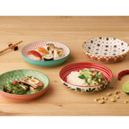 Vier bunte Keramikschalen mit verschiedenen Mustern auf Holztisch, gefüllt mit Sushi, Reis und Snacks.