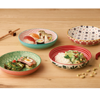 Vier bunte Keramikschalen mit verschiedenen Mustern auf Holztisch, gefüllt mit Sushi, Curry, Sandwich und leer.