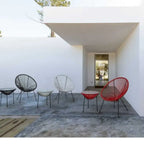 Moderne Gartensessel Spaghetti Parker in Schwarz, Weiß und Rot auf Terrasse unter Überdachung.