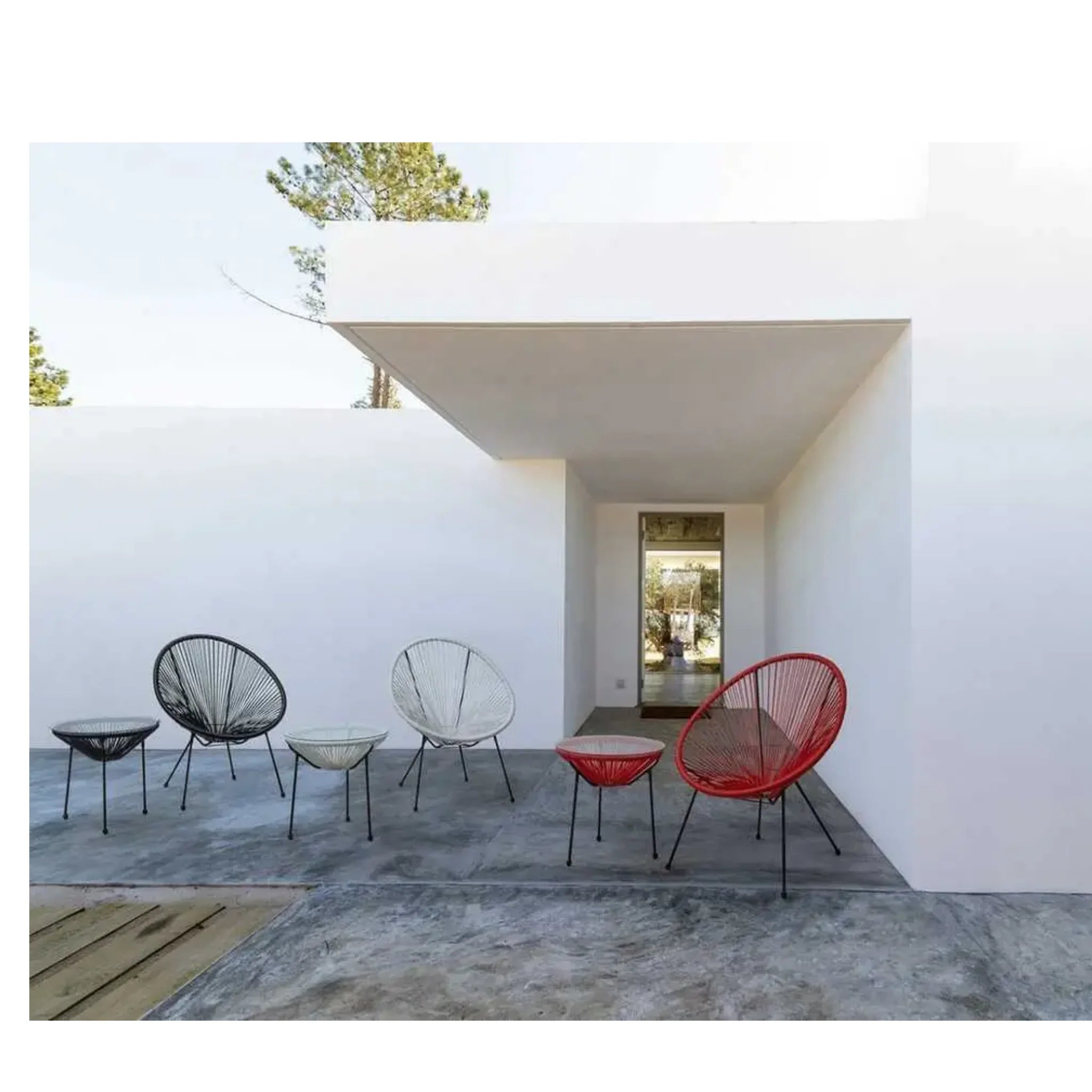 # Alt-Text:

Moderne Gartenmöbel: Bunte Lounge-Stühle und Beistelltische auf Terrasse mit weißer Architektur