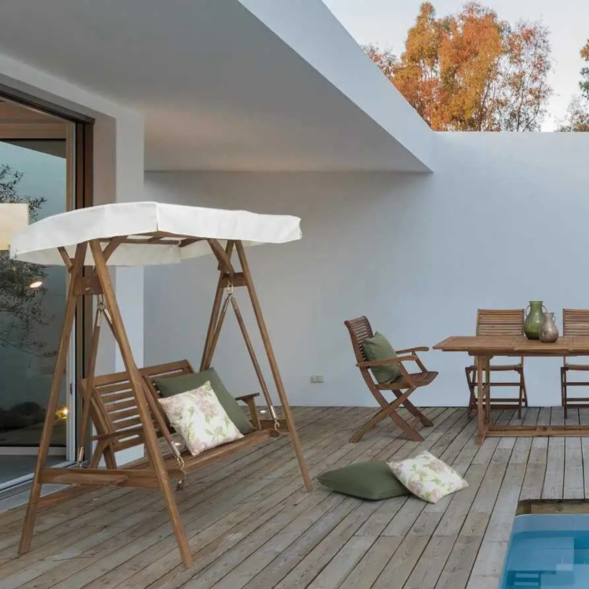 Holz-Hollywoodschaukel Noemi mit weißem Dach und Kissen auf Terrasse mit Pool und Gartenmöbel-Set