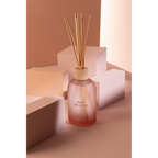 Jolipa Duftspender "Rose Rêveuse" in rosa Flakon mit Rattanstäbchen und Holzdeckel auf hellem Podest
