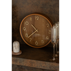 Runde Wanduhr aus dunklem MDF-Holz mit goldenen Zeigern und Ziffern, dekorativ an Wand gelehnt