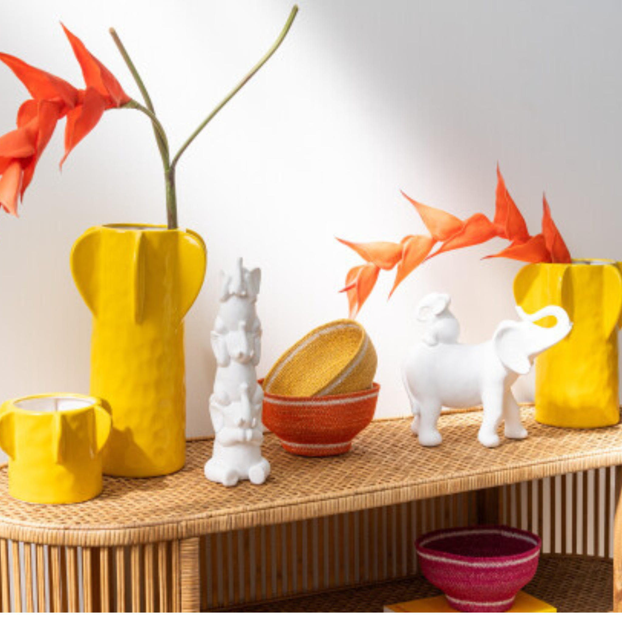 Weiße Elefantenpyramide Deko mit gelben Vasen und orangen Blüten auf Holzkommode
