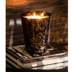 Luxus Duftkerze Noa Sandelholz Small von Jolipa - Elegante Kerze in schwarzem Glas auf Bücherstapel, warm leuchtend für gemüt