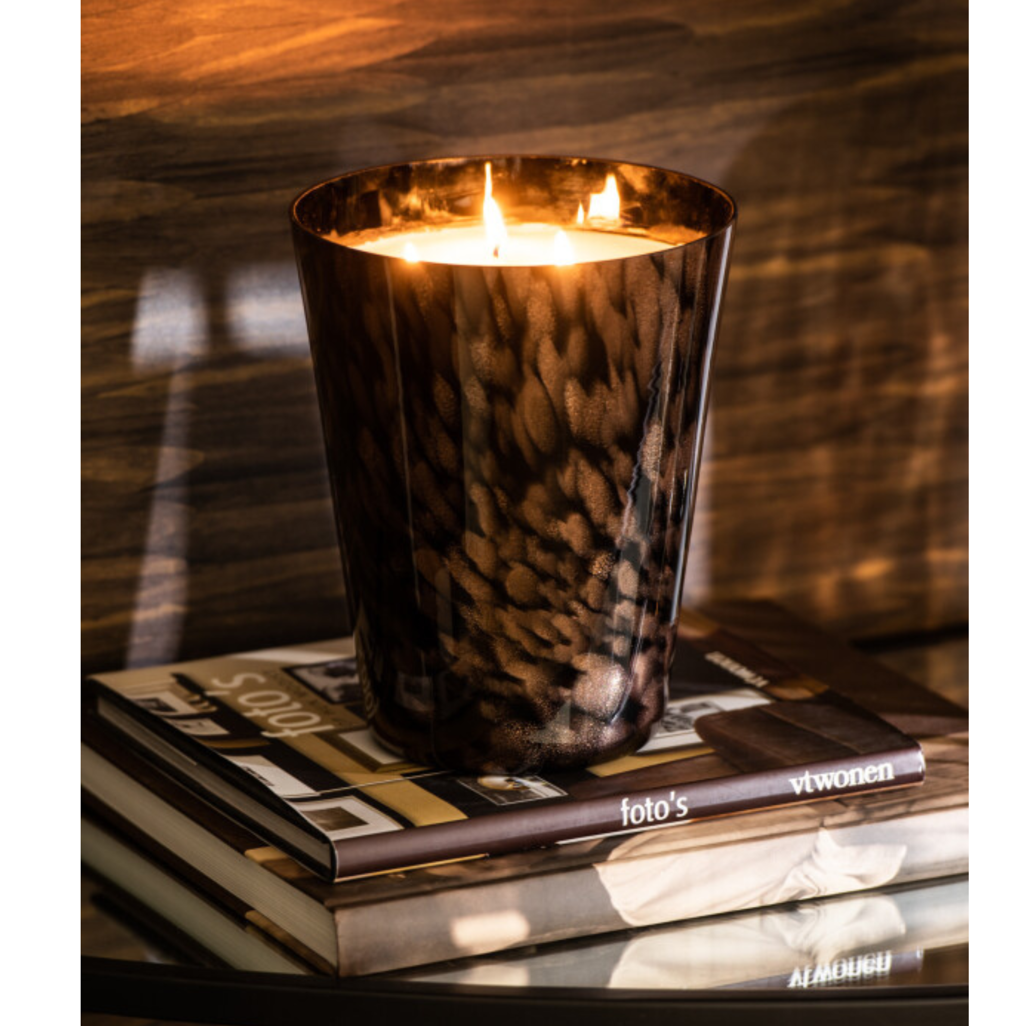 Luxus Duftkerze Noa Sandelholz Small von Jolipa - Elegante Kerze in schwarzem Glas auf Bücherstapel, warm leuchtend für gemüt