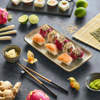 Elegante Sushi-Platte mit Lachs, Thunfisch und Sesam auf grauem Hintergrund mit Stäbchen.
