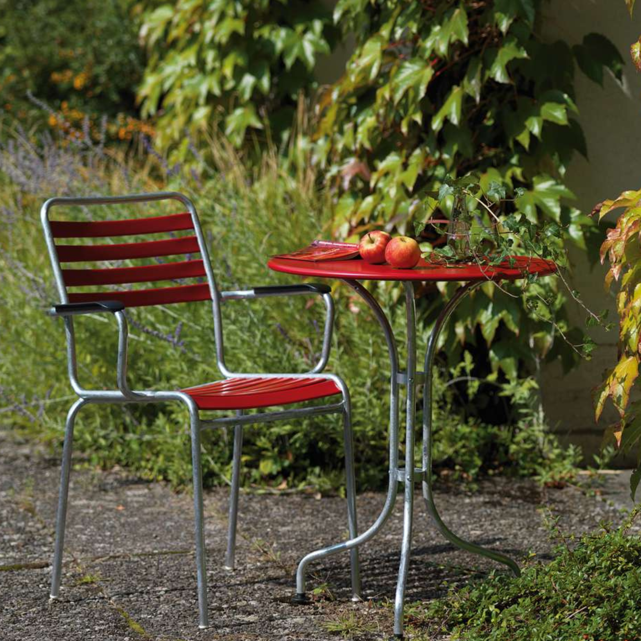 Schaffner Metalltisch St. Moritz 60cm rot rund - moderner Gartentisch mit Stuhl im grünen Garten