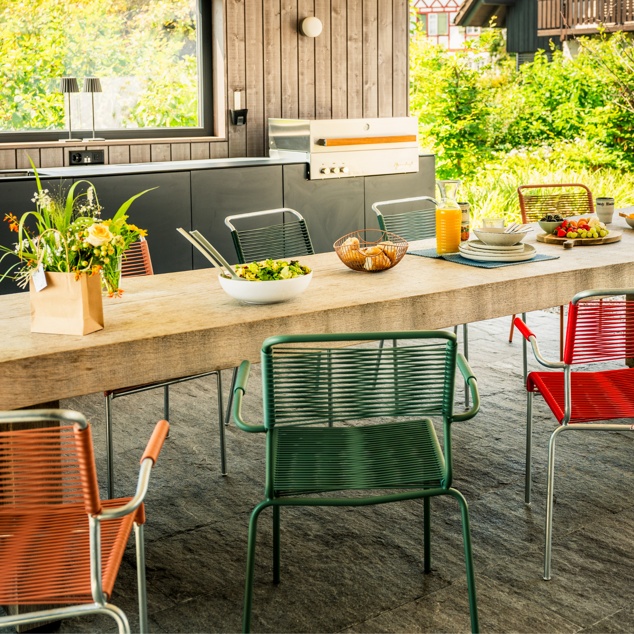 Schaffner Spaghetistühle in Grün und Rot um Holztisch im modernen Gartenzimmer