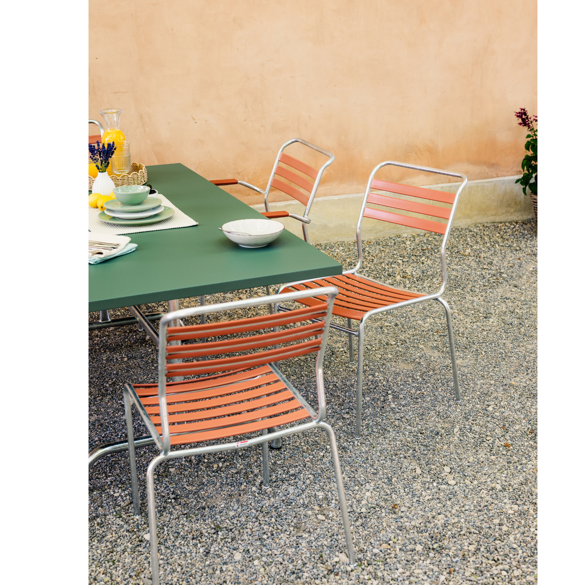 Schaffner Sänti Lattenstuhl in Orange und Pastellgrün mit Tisch im Freien