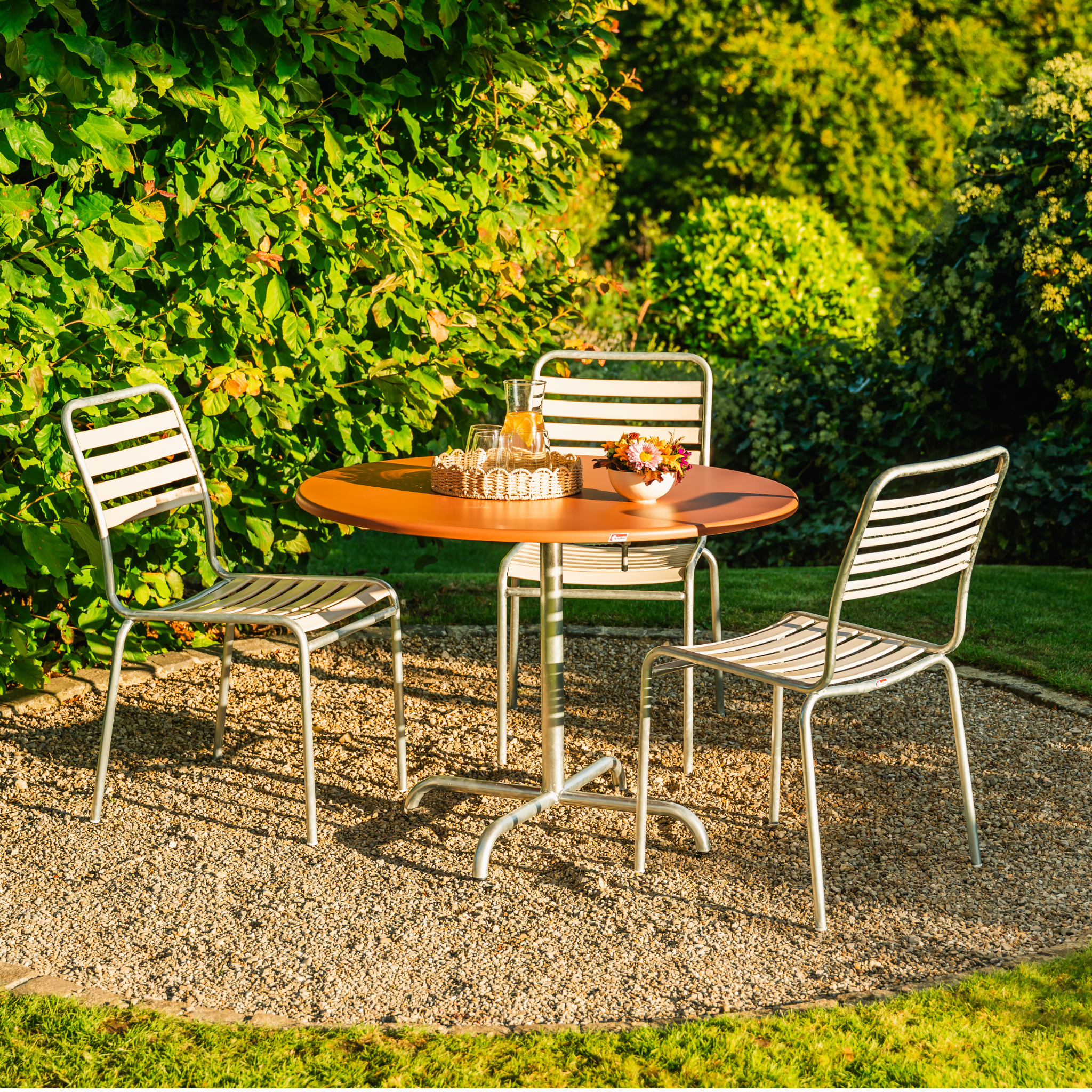 Schaffner Fiberglas Tisch Davos 100cm rot rund mit Aluminium Stühlen im Garten