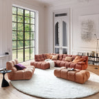 Modernes Wohnzimmer mit terracottafarbenem Polstermöbel Set, rundem Teppich und großem Fenster.