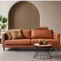 Cognacfarbenes Leder-Sofa mit Kopfstütze vor Holzlamellen-Bogen in modernem Wohnzimmer mit rundem Couchtisch