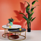 KARE Design Couchtisch-Set mit Marmor-Optik und goldenem Gestell, dekoriert mit Pflanzen vor korallenroter Wand