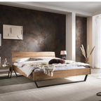 Modernes Holzbett mit Metallfuß, elegantes Schlafzimmer mit dunkler Akzentwand und natürlicher Beleuchtung.
