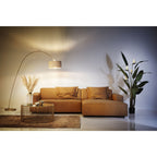 Elegantes Wohnzimmer mit cognacfarbenem Sofa, goldenem Bogenlampe und Beistelltisch von KARE Design